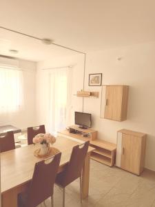 a dining room with a table with chairs and a television at Apartments Niko Novalja in Novalja
