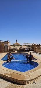 a group of people sitting around a swimming pool at Riad Berber in Merzouga +19 photos