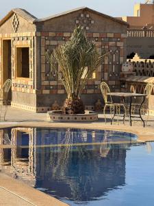 a pool with a table and chairs next to a building at Riad Berber in Merzouga