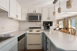 a kitchen with white cabinets and a stove top oven at Snowshoe Ski-InSki-Out Steps to Ballhooter Lift Mountain Lodge Condo in Snowshoe +58 photos