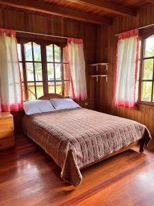 a bedroom with a bed in a room with windows at Hospedaje Cabañas Wohlrab in Oxapampa