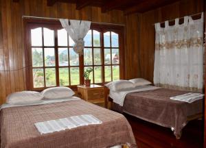 two beds in a room with a window at Hospedaje Cabañas Wohlrab in Oxapampa