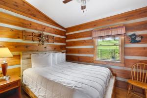 a bedroom with wooden walls and a bed and a window at 2BR Cabin with Jacuzzi and Mountain Views - Cabin 5 in Fancy Gap