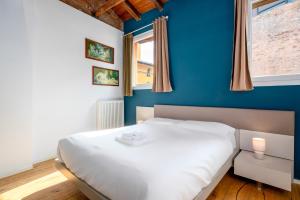 a bedroom with a white bed and a blue wall at Appartamento Elegante con 2 Camere nel Centro Storico di Bologna in Bologna