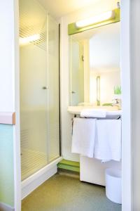 y baño con ducha y toallas blancas. en ibis budget Valenciennes Petite-Forêt, en Petite Forêt
