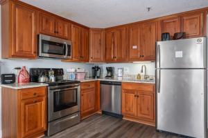 a kitchen with wooden cabinets and stainless steel appliances at ML 345 Ski-InOut Slope Views Sleeps 6 Steps to Ballhooter in Snowshoe +51 photos