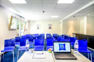 une salle de conférence avec des chaises bleues et un ordinateur portable sur une table dans l'établissement ibis budget Valenciennes Petite-Forêt, à Petite-Forêt