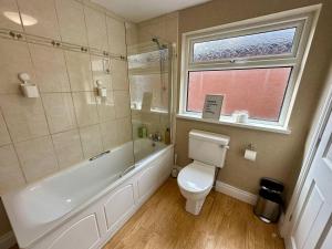 a bathroom with a tub and a toilet and a window at 2br Ormeau central in Belfast