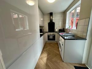 a white kitchen with a sink and a dishwasher at 2br Ormeau central in Belfast +10 photos