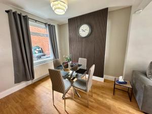 a living room with a table and chairs and a clock at 2br Ormeau central in Belfast