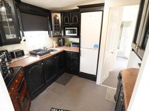 a kitchen with black cabinets and a white refrigerator at Towervans Z11 in Mablethorpe +14 photos