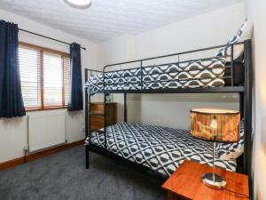 a bedroom with two bunk beds and a table at 36 Cae Rhos in Holyhead