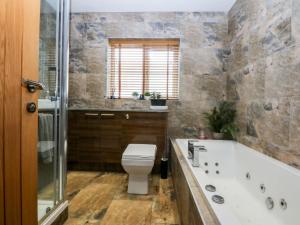 a bathroom with a bath tub and a toilet at 36 Cae Rhos in Holyhead +20 photos