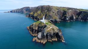an island in the water with a lighthouse on it at 36 Cae Rhos in Holyhead