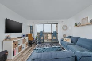 a living room with a blue couch and a tv at 2971 - Seabbatical in Duck