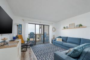 a living room with a blue couch and a balcony at 2971 - Seabbatical in Duck