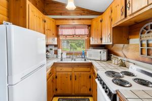 a kitchen with wooden cabinets and a white refrigerator at 2BR Cabin with Jacuzzi and Mountain Views - Cabin 5 in Fancy Gap