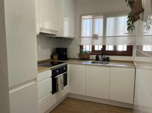 a white kitchen with white cabinets and a stove at Chalet Las Meninas in Denia