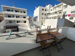 two chairs and a table on a balcony with buildings at Casa aOrta Apartments in Faro