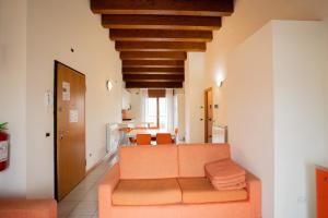 a living room with an orange couch and a kitchen at Residence Roberta - Agenzia Arcobaleno in Caorle +39 photos
