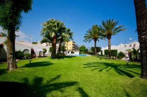 a green park with palm trees and a building at Chalet Las Meninas in Denia