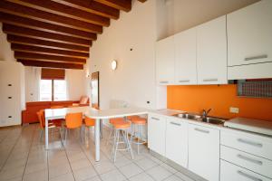 a kitchen with white cabinets and orange accents at Residence Roberta - Agenzia Arcobaleno in Caorle