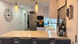 a kitchen with a counter with chairs and a clock on the wall at Apartamentos Calanegra con Piscina y Solárium en Puerto de Mazarrón Costa Cálida in Murcia