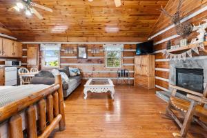 a log cabin living room with a couch and a fireplace at Hillside Hideout Log Cabin For 2! Cabin 10 in Fancy Gap