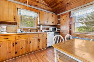 a kitchen with wooden cabinets and a white stove top oven at Hillside Hideout Log Cabin For 2! Cabin 10 in Fancy Gap +20 photos