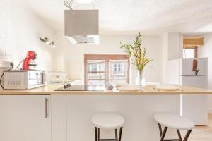 a kitchen with white cabinets and a counter with stools at Duplex Centre historique in Strasbourg