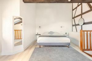 a white bedroom with a bed and a mirror at Duplex Centre historique in Strasbourg