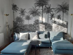 a living room with a blue couch and palm trees at The Stage Door Apartment in Debrecen