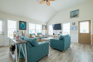 a living room with two blue chairs and a tv at 7676 - Nautical by Nature in Avon