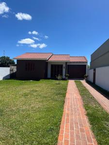 a house with a brick pathway in front of a yard at Comfortable home, close to everything! in Caçapava do Sul +2 photos