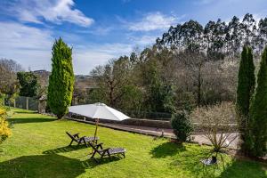 a park with two picnic tables and a white umbrella at Vivienda Vacacional La Seronda in Ribadesella
