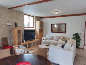 a living room with white furniture and a tv at Moulin Morin Domaine historique aux portes de Bayeux in Vaucelles