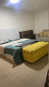 a bedroom with a large bed with a yellow tufted mattress at Lozi House Cozy Stay in Al Azraq ash Shamālī