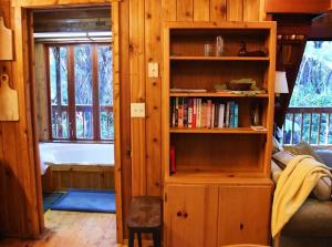 a living room with a book shelf and a bath tub at Beautiful Cedar Cottage in Volcano in Volcano