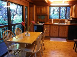 a kitchen with a wooden table and chairs and a kitchen with a sink at Beautiful Cedar Cottage in Volcano in Volcano