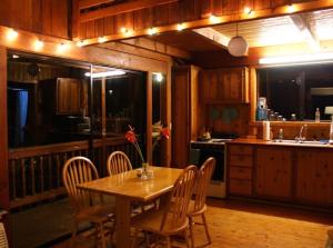 a kitchen with a wooden table and chairs and a kitchen with a sink at Beautiful Cedar Cottage in Volcano in Volcano +14 photos