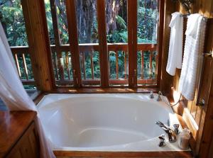 a large white tub in a bathroom with a window at Beautiful Cedar Cottage in Volcano in Volcano