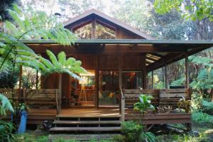 a wooden cabin with benches in a forest at Beautiful Cedar Cottage in Volcano in Volcano
