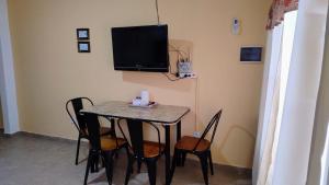 a dining room table with chairs and a tv on the wall at Depto B in Rincon de los Sauces