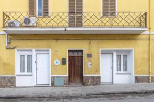 a yellow building with three doors on a street at Terra e Mare Apartments II- Terra in Sorso