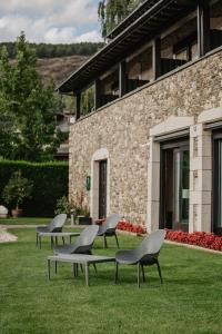 a group of chairs sitting in the grass in front of a building at Hotel Bernat de So in Llivia