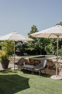 two chairs and a bench under umbrellas next to a pool at Hotel Bernat de So in Llivia