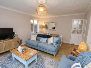 a living room with a blue couch and a tv at Seashells at Runswick Lodge in Saltburn-by-the-Sea