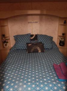 a bedroom with a large bed with blue and white sheets at L'ancyze in Le Torp-Mesnil