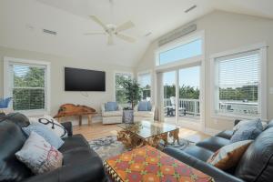 a living room with a couch and a table at 1064 - Sunset Cottage in Corolla +65 photos
