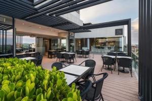 eine Terrasse mit Tischen und Stühlen auf einem Balkon in der Unterkunft The Hub Urban Hotel in Asunción